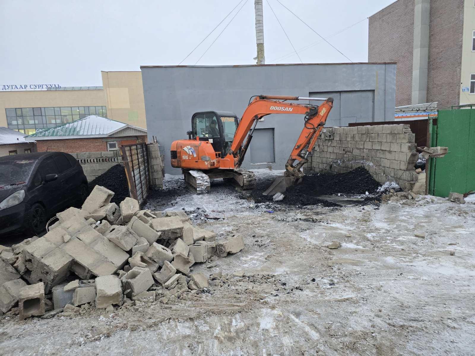 Экскаватор ашиглан хуучин нүүрсний зуухны хашааг буулгаж, талбайг бэлтгэж буй байдал.